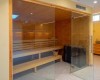 Moderní sauna s dřevěnými lavicemi a skleněnými dveřmi.