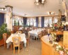 Restaurace s dřevěnými stoly, židlemi a dekoracemi, s ubrusy a květinami.