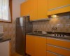 Malá kuchyně s oranžovými skříněmi a retro obkladem.