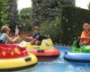 Děti řídí barevné nárazníkové čluny na vodní atrakci venku.