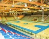 Vnitřek sportovní haly s basketbalovým hřištěm a prázdnými tribunami.  