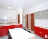 Moderní kuchyň s červenými a bílými skříňkami a jídelním stolem.