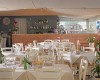 Elegantně prostřená restaurace s dřevěným barem v pozadí a uspořádáním stolů s bílými židlemi.