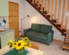 Obývací pokoj s pohovkou, schodištěm a jídelním stolem s vázou slunečnic.