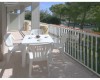 Prostorný balkon s plastovým stolem, čtyřmi židlemi a šálky.