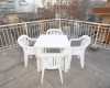 Bílý plastový jídelní stůl se čtyřmi židlemi na terase.