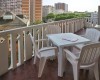 Plastový stůl a židle na balkoně s výhledem na městskou zástavbu.