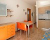 Kuchyňský kout s oranžovým nábytkem a jídelním stolem se čtyřmi židlemi.