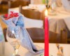 Stůl v restauraci se zapálenou červenou svíčkou a ozdobenou sklenicí.