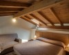 Podkrovní ložnice s dřevěným stropem, manželskou postelí a pohovkou.
