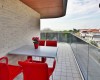 Balkon s červenými židlemi, stolem a květináčem s rostlinou.