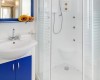 Moderní koupelna s modrou skříňkou a bílým sprchovým koutem.