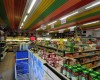 Interiér samoobsluhy s barevným stropem a plnými regály potravin.