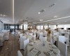 Elegantní restaurace s kulatými stoly pokrytými bílými ubrusy a židlemi s potahy.