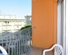 Balkón s oranžovými stěnami, plastovou židlí a výhledem na okolní budovy.