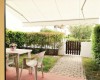 Terasa se zahradním nábytkem, výhledem na keře a dřevěnou branku.