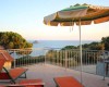 Terasa s lehátky a slunečníkem s výhledem na moře a ostrov.