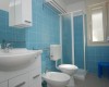 Modře obložená koupelna se sprchovým koutem, umyvadlem, toaletou a bidetem.
