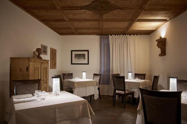 Interiér elegantní restaurace s dřevěným stropem a několika stoly.