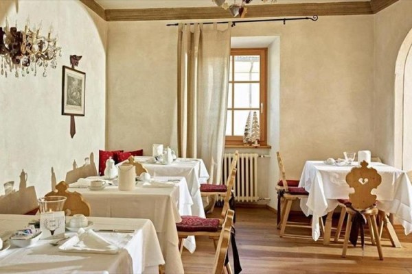 Restaurace se stolky pokrytými bílými ubrusy v rustikálním stylu.