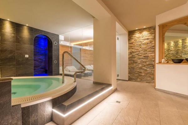 Wellness s vířivkou a odpočinkovou zónou ve světlém moderním interiéru.