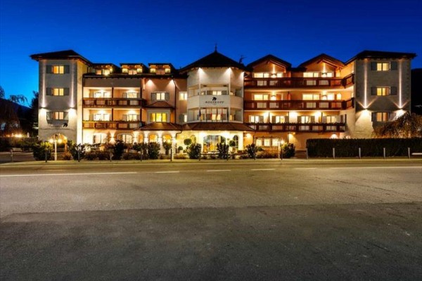 Budova hotelu v noci s rozsvícenými světly a modrou oblohou.