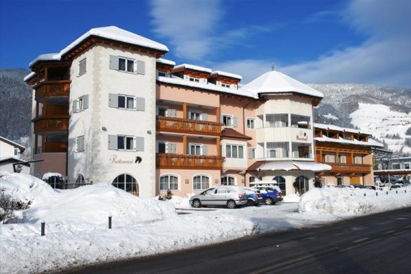 Hotel v zasněžené horské krajině s modrou oblohou.