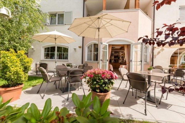 Terasa s několika stoly a slunečníky před kavárnou nebo restaurací.