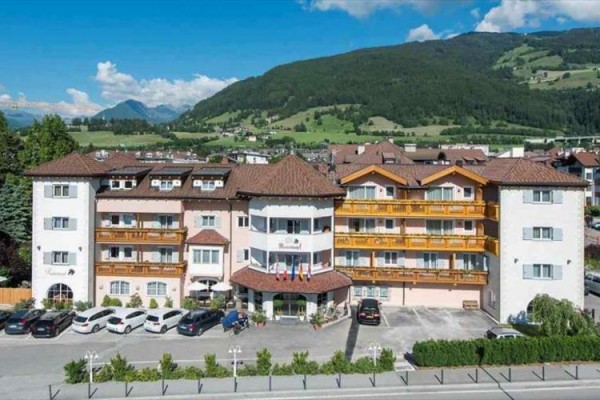 Hotel obklopený horami a zaparkovanými auty.