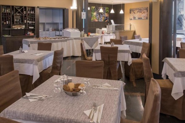 Restaurace s prostřenými stoly a bufetovým stolem v pozadí.