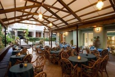 Střešní terasa s proutěným nábytkem a prostřenými stoly ve venkovní restauraci.