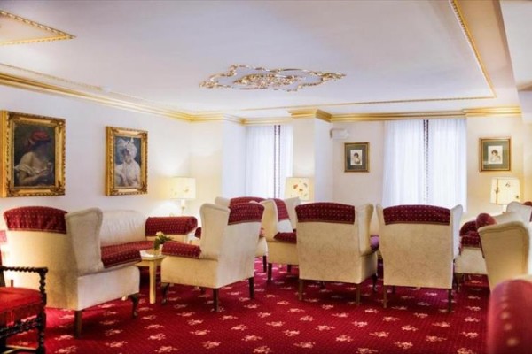 Elegantní obývací prostor s červenými a krémovými křesly a obrazy na stěnách.