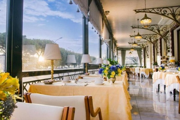 Elegantní restaurace s prostřenými stoly a výhledem na venkovní krajinu.