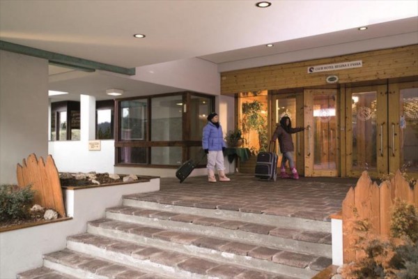 Dvě děti s kufry vstupují do budovy hotelu.