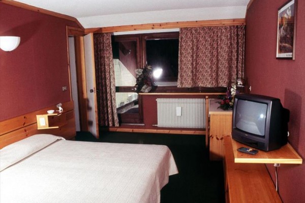 Hotelový pokoj s postelí, televizí a balkonem.