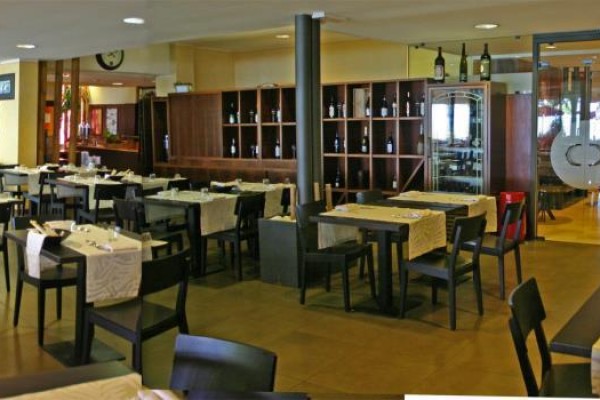 Prostorná restaurace se stoly zakrytými světle béžovými ubrusy.