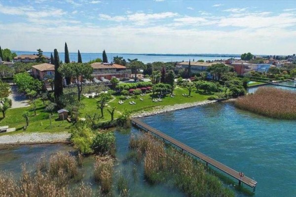 Pohled na zelený park s budovami u jezera a dřevěným molem.