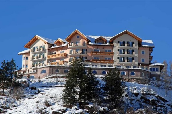 Luxusní hotel na zasněženém kopci proti modré obloze.