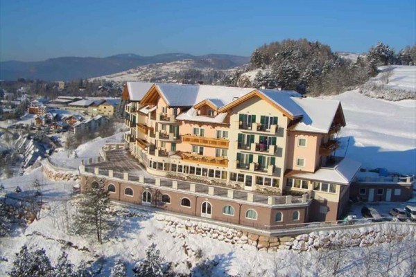 Velký hotel s barevnými fasádami v zasněžené horské krajině.
