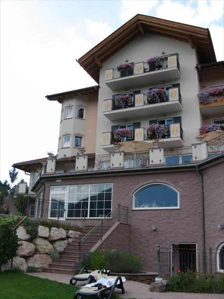 Budova hotelu s balkony zdobenými květinami.