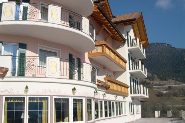 Budova hotelu s balkony a horami v pozadí.
