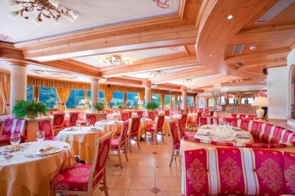 Elegantní restaurace s červenými a zlatými detaily a velkými okny.