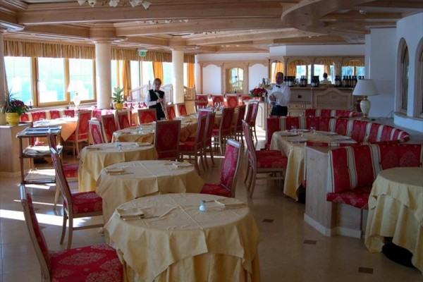 Restaurace s dřevěným interiérem, červenými židlemi a žlutými ubrusy.
