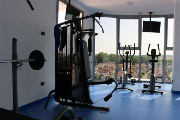 Posilovna s moderními fitness stroji v místnosti s velkými okny nabízející výhled na město.