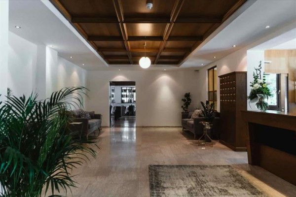 Elegantní hotelová lobby s dřevěným stropem a rostlinami.