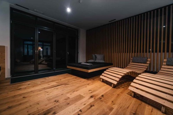 Moderní relaxační místnost s dřevěnými lehátky a lavicí.