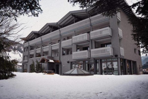 Třípatrová budova s balkony obklopená zasněženou krajinou.