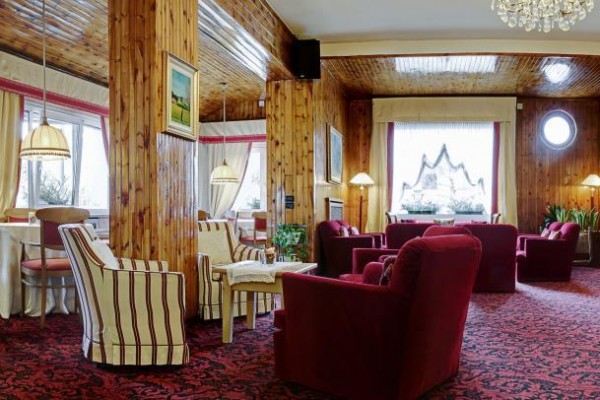 Elegantní hotelová lounge s červenými křesly a dřevěným obložením.