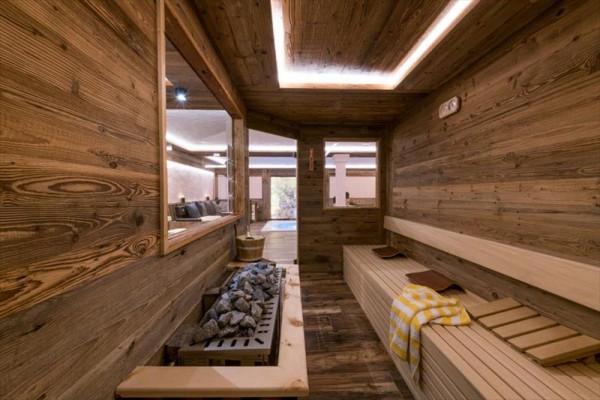 Sauna se dřevěným interiérem, lavicemi a vyhřívacími kameny.