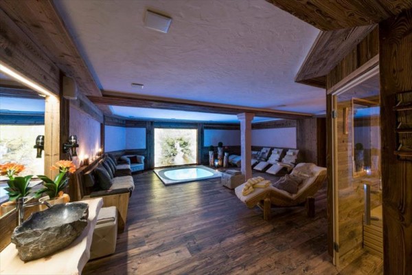 Luxusní wellness místnost s vířivkou, lehátky a dřevěným obložením.